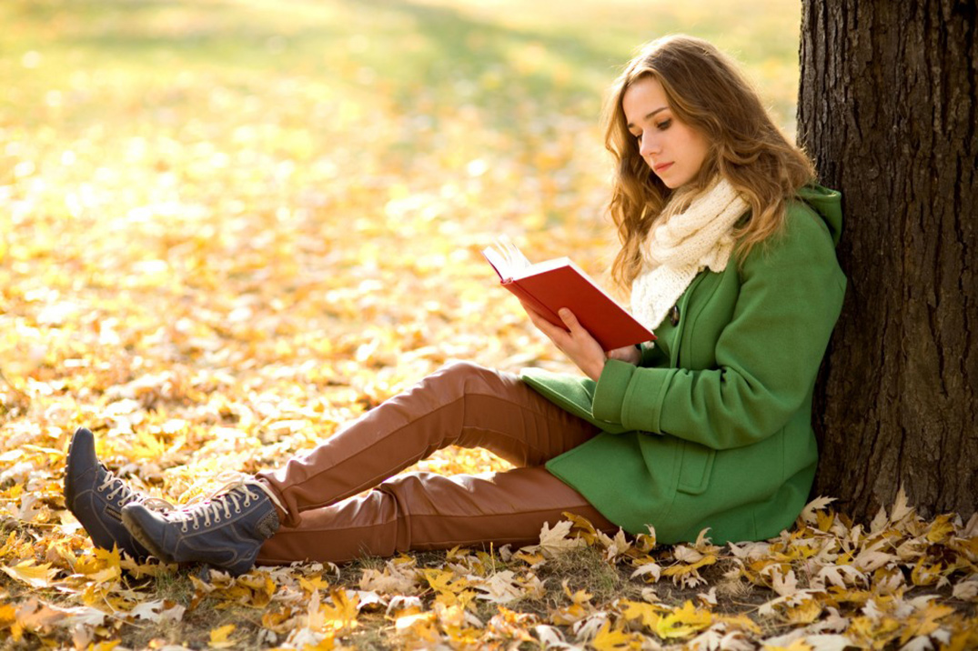 Una chica leyendo bajo un árbol