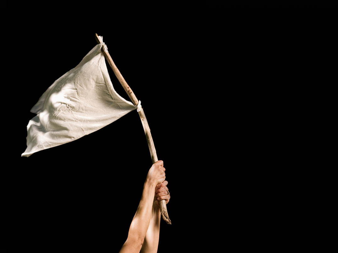 Unos brazos sosteniendo una bandera blanca de rendición