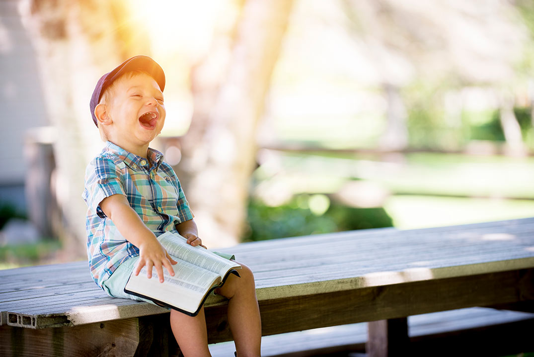 Niño riéndose con una Biblia